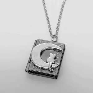 Detailed view of a vintage silver book locket necklace featuring a cat on a crescent moon