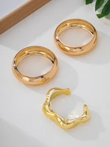 Modern 3-piece gold bangle set featuring an irregular wavy open cuff and smooth rings
