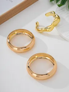Close-up of a 3-piece gold bangle set featuring an irregular textured open cuff