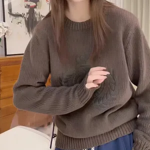 Close-up of a Korean style brown cable knit sweater with an embossed chest emblem