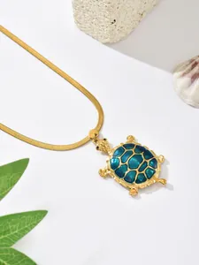 Detailed macro view of gold-plated turtle pendant with teal enamel on snake chain.