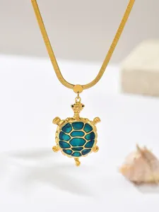 Detailed macro view of a gold-plated stainless steel turtle necklace with blue teal shell