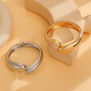 Detailaufnahme von unregelmäßigen gold- und silberfarbenen Armreifen mit funkelnden Steinen.