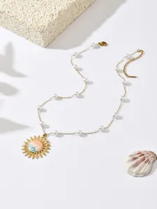 Detailed view of a gold-plated necklace featuring an ocean wave pendant and white pearls