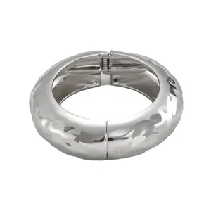 Detailansicht eines silbernen, klobigen Armreifs mit gehämmerter Metalloberfläche