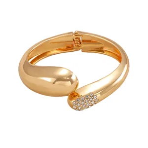 Detailansicht eines goldfarbenen Armreifs in Wassertropfenform mit Glitzersteinen