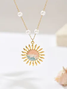 Detailed view of an elegant gold sun pendant necklace with blue wave enamel and pearls