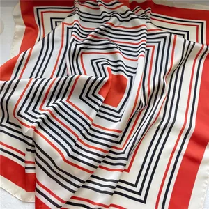 Close-up of square silk-like scarf with elegant red and black geometric stripes.