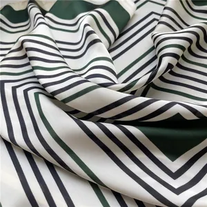Detailed view of the smooth texture and green geometric striped pattern of a silk-like scarf