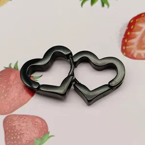 Detailed macro view of black titanium steel heart-shaped ear clips on a cute background