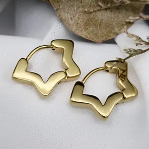 Detailed close-up view of gold star shaped stainless steel hoop earrings on white fabric