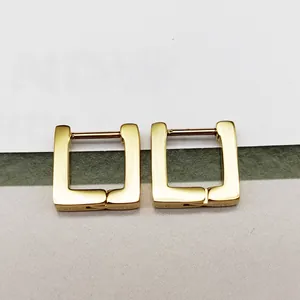 Macro detail of polished gold-finished square hoop earrings made of titanium steel