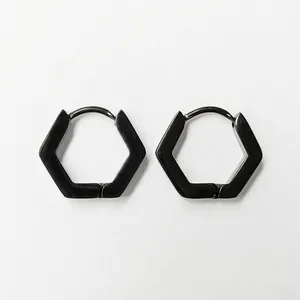Detailed view of matte black hexagonal titanium steel hoop earrings on white texture