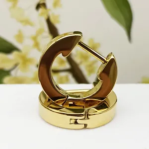 Detailed close-up of polished gold titanium steel hoop earrings with secure clasp