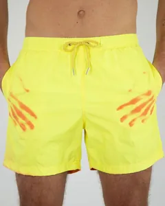 Close-up of neon yellow men's swim trunks with orange color-changing handprints
