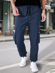 Vista dettagliata dei pantaloni cargo blu scuro da uomo con coulisse e tasche multiple