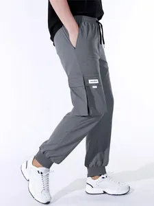Vista laterale dettagliata dei pantaloni cargo grigi da uomo con coulisse e tasche multiple