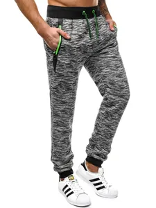Gros plan d'un jogging chiné avec cordon vert néon et poches zippées détaillées.