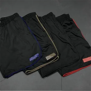 Gros plan de quatre shorts de sport noirs pour hommes avec des liserés colorés
