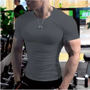 T-shirt de compression sport gris foncé moulant pour hommes dans une salle de gym.