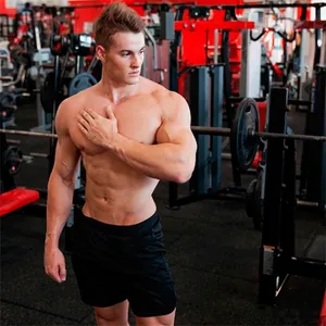 A professional athlete wearing black gym shorts posing in a modern fitness center