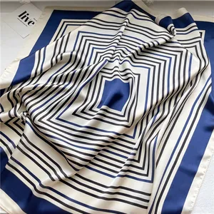 Detail of a navy blue and white striped silk-like square scarf with geometric pattern