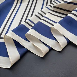 Detailed close-up showing the fine stitching on a navy blue and white striped silk-like scarf