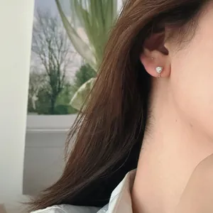 Close-up of a silver heart-shaped zircon earring worn on ear, highlighting detail
