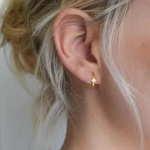 Elegante goldene Creolen mit quadratischem Zirkonia-Stein an einem weiblichen Model