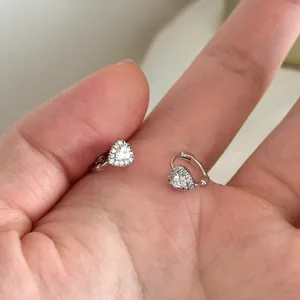 Detailed view of elegant silver heart-shaped zircon hoop earrings held in a hand