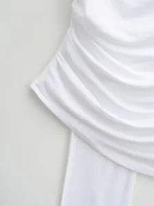 Close-up detail of high-quality white ruched fabric on a trendy designer summer top.
