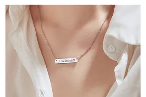 Close-up detail of a minimalist silver bar necklace featuring custom Elizabeth engraving.