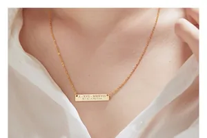 Close-up of personalized gold bar necklace with custom date and initials engraving.