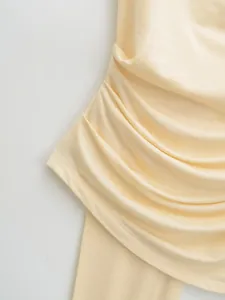 Close-up macro shot of elegant ruched fabric detail on a pale yellow summer halter neck top