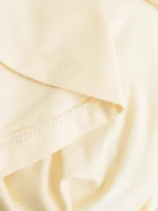 Close-up macro detail of high-quality stitching on a cream yellow halter neck camisole