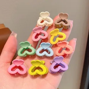 Detailed view of ten colorful heart-shaped mini hair claw clips in palm