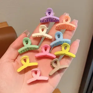 Detailed view of various colorful mini matte hair claw clips held in hand for children