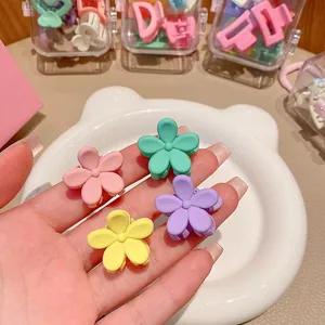Close-up of hand holding four colorful pastel flower-shaped mini hair claw clips