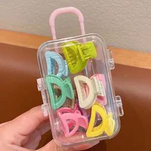 Macro view of colorful mini hair claw clips stored in a cute clear suitcase packaging box