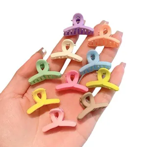 Assorted set of colorful mini pastel hair claw clips for girls and kids held in hand.