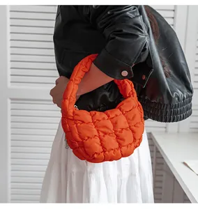 Dettaglio di una borsa a nuvola trapuntata arancione vivace tenuta da una modella.