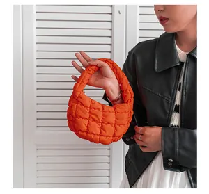 Dettaglio di borsa a mano nuvola trapuntata arancione brillante tenuta da modella