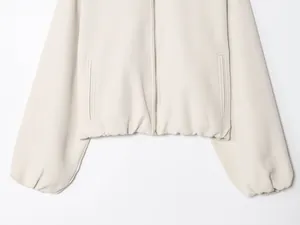 Detail view of a beige women's zipper jacket with side pockets and a puffy hem.
