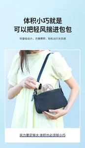 Detailed shot of a compact white handheld fan being placed inside a stylish black bag