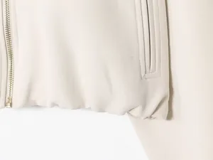 Detailed view of the metal zipper and fabric texture on a beige women's jacket