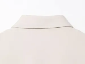Close-up detail of a minimalist beige jacket collar featuring precise stitching
