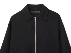 Detailed close-up of a minimalist black women's zip-up jacket with polo collar