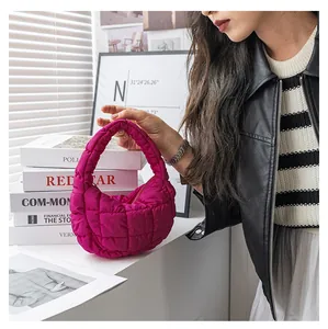 Elegante borsa fucsia trapuntata a nuvola tenuta da una modella, texture imbottita