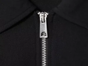 Close-up detail of a smooth metal silver zipper on a premium black women's fashion jacket