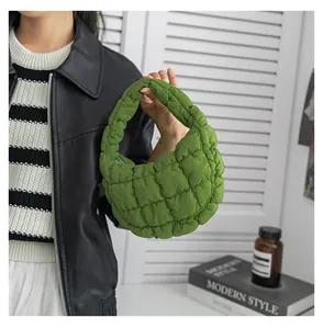 Dettaglio di una borsa a mano nuvola trapuntata verde tenuta da una modella